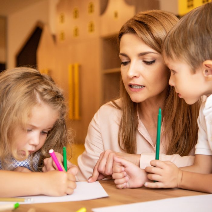 educator and children drawing together in kindergarten